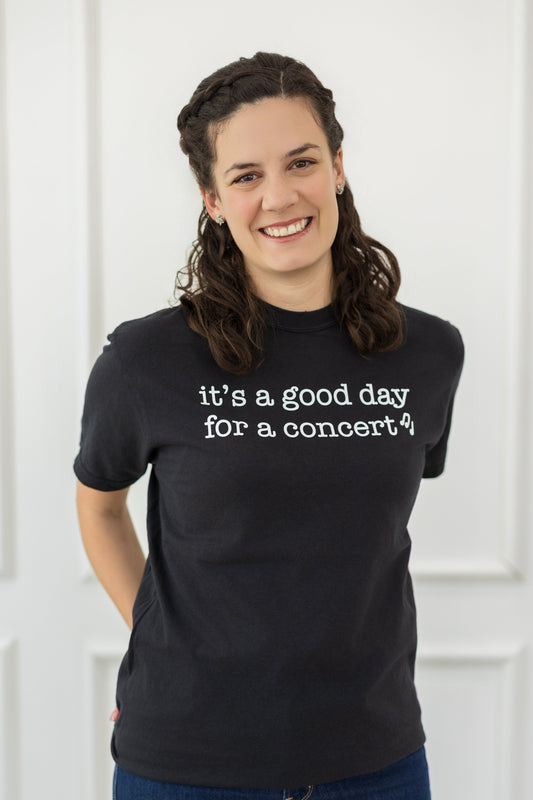 Person wearing a black t-shirt with 'it's a good day for a concert?' text against a white background