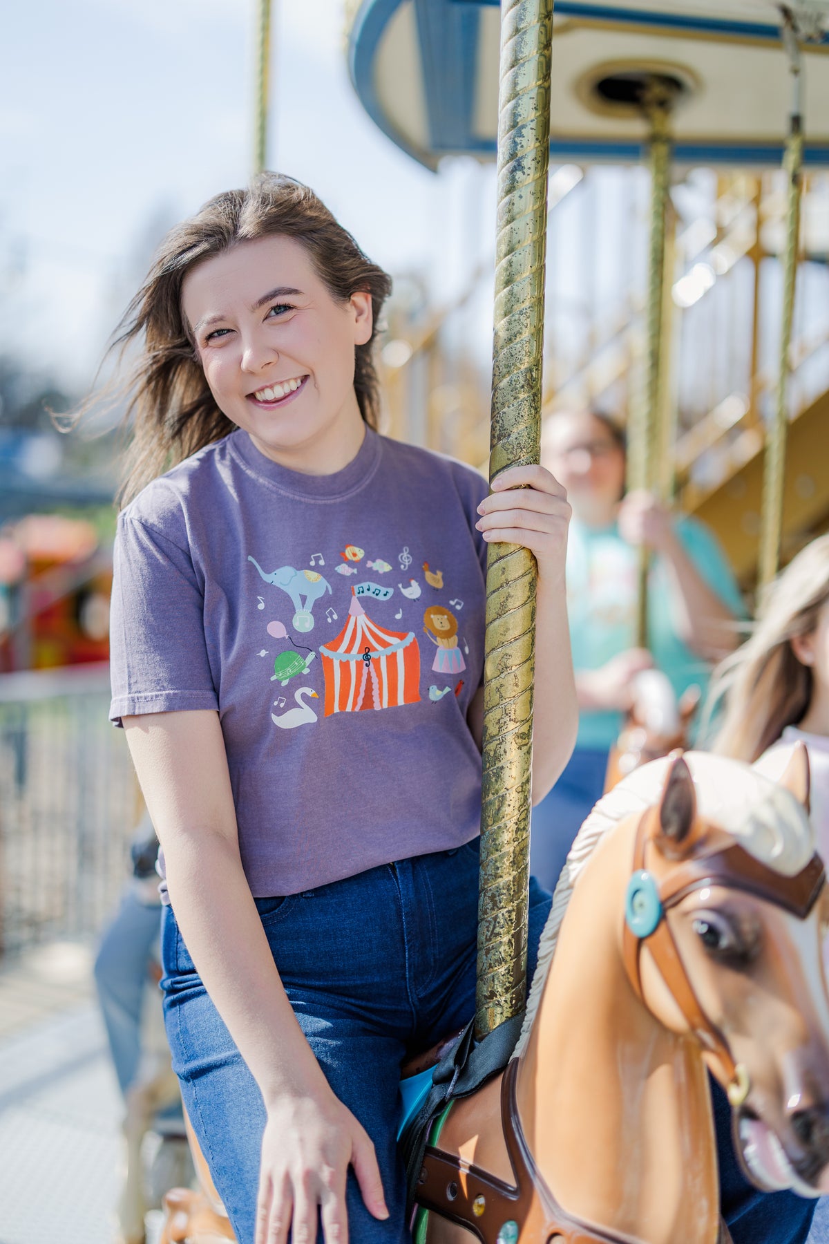 Person on a carousel with a purple t-shirt featuring a colorful design.
