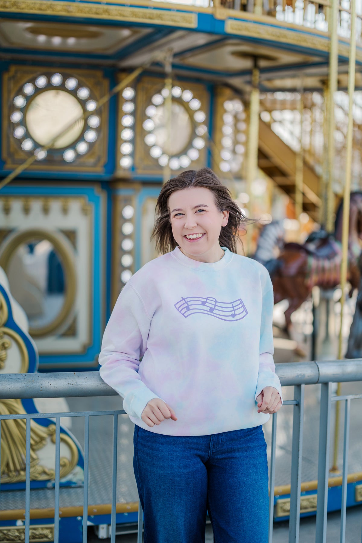 Person wearing a colorful sweater in front of a carousel