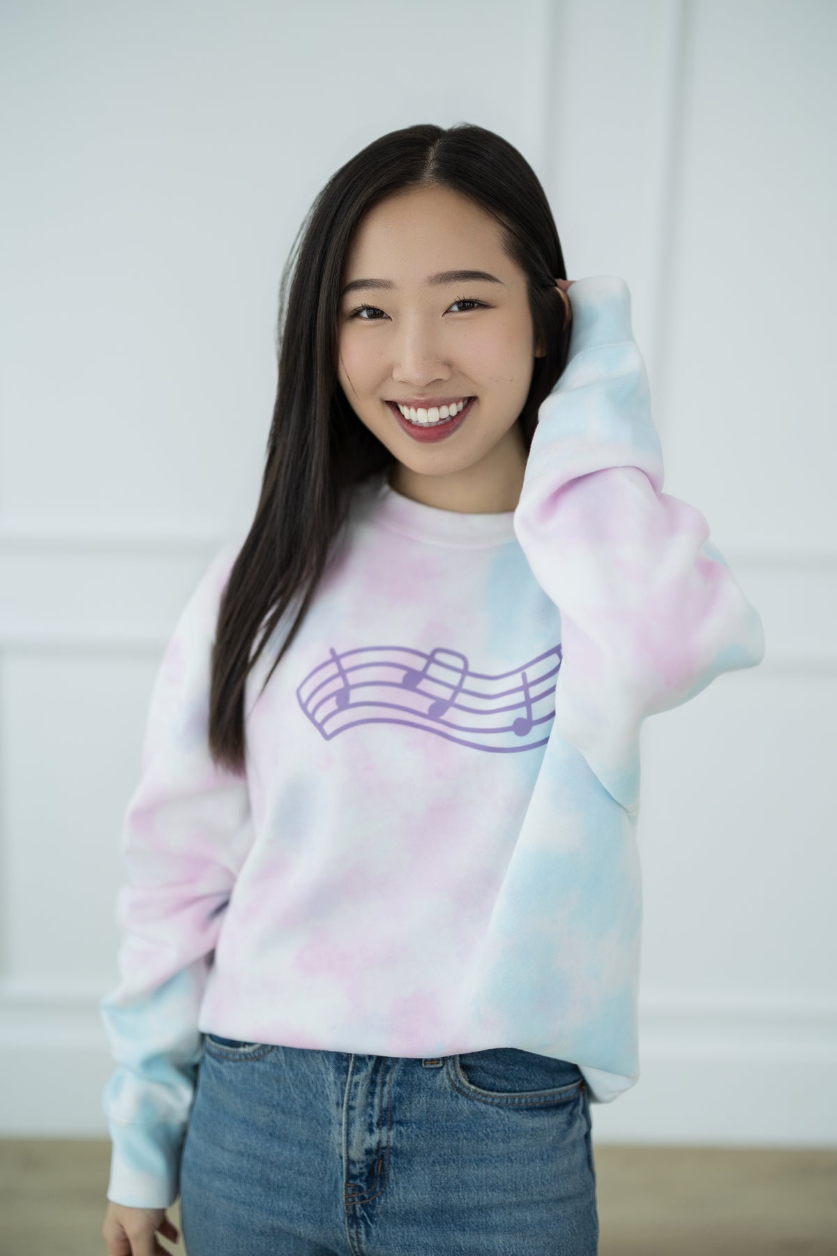 Person wearing a tie-dye sweatshirt with a music note design against a plain background
