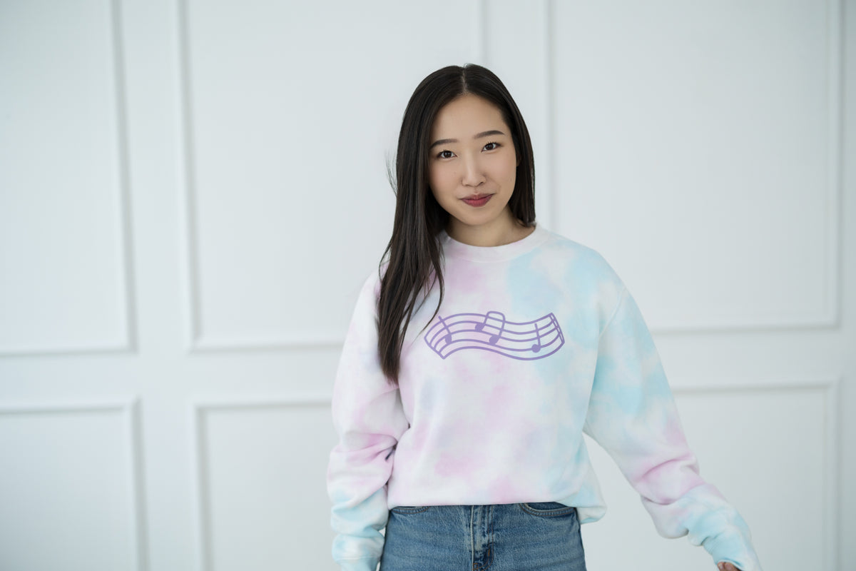 Person wearing a tie-dye sweatshirt with a graphic design against a white background
