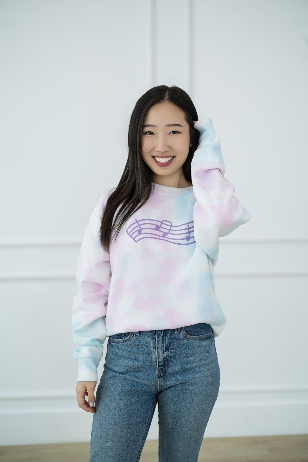 Person wearing a tie-dye sweatshirt with a music note design against a white background
