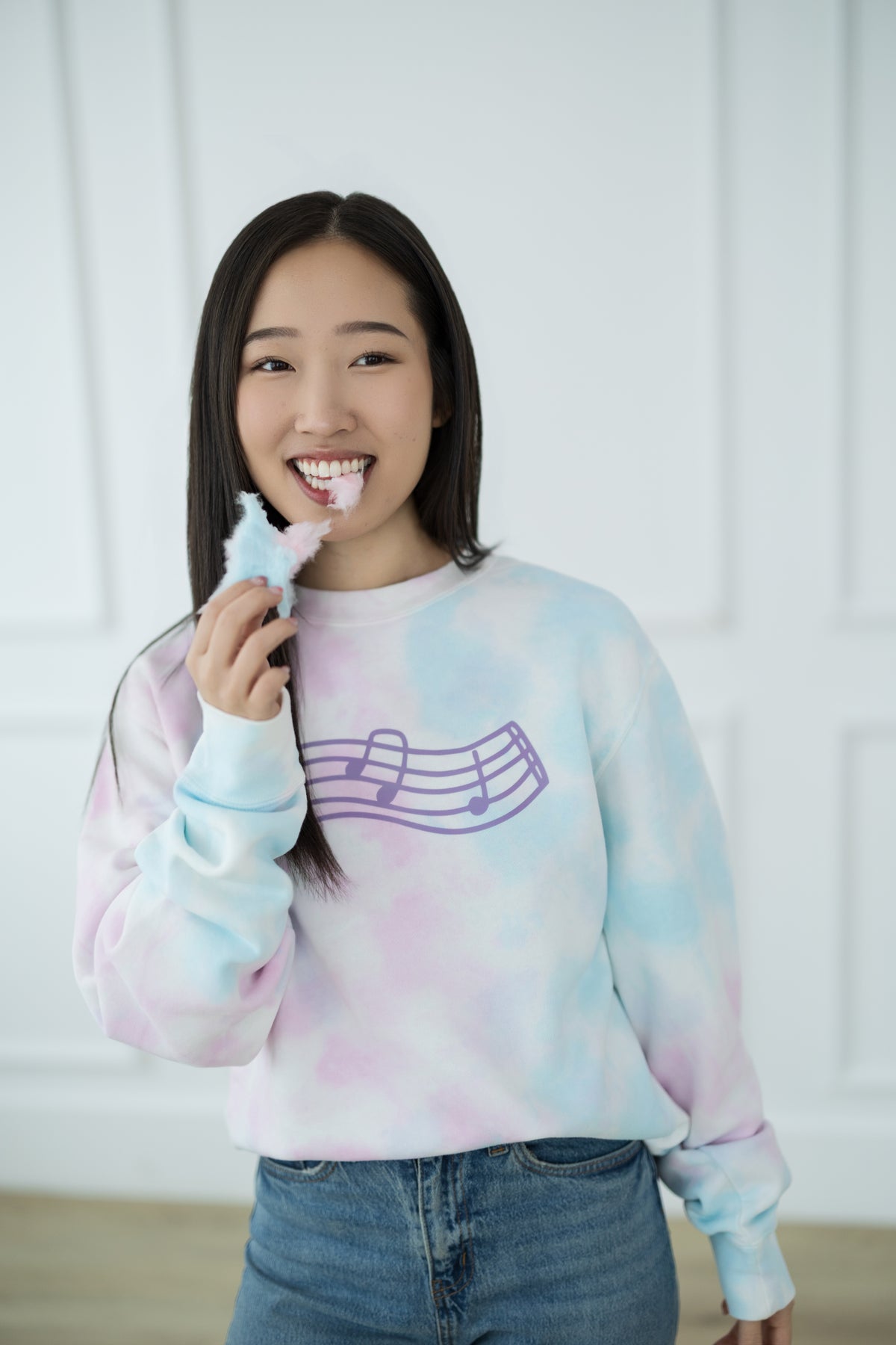 Person wearing a tie-dye sweatshirt with a music note design against a white background