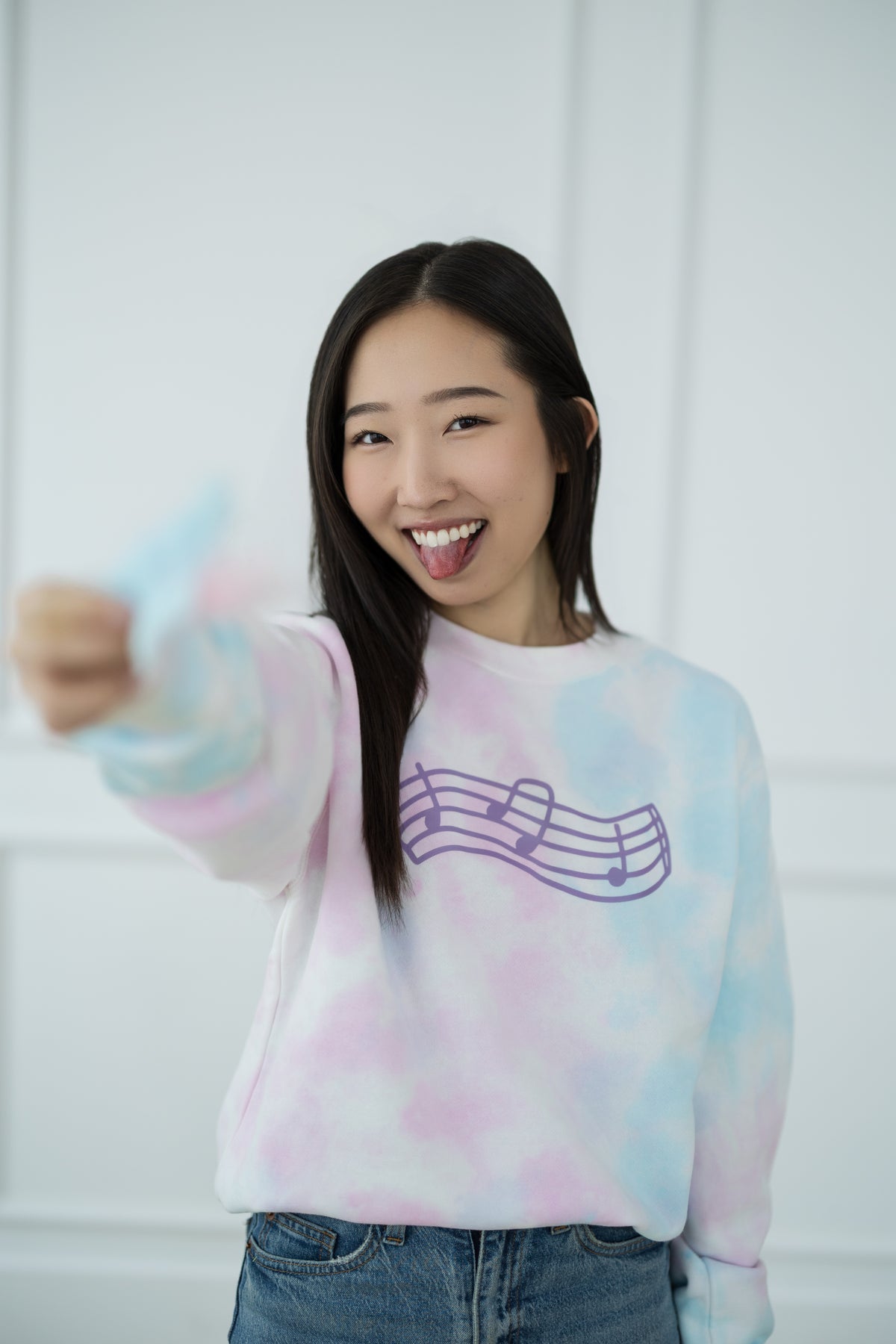 Person wearing a tie-dye sweater with a music note design, holding cotton candy.