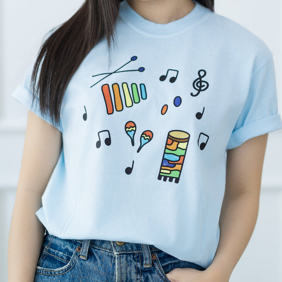 Woman wearing a light blue t-shirt with colorful designs against a white background