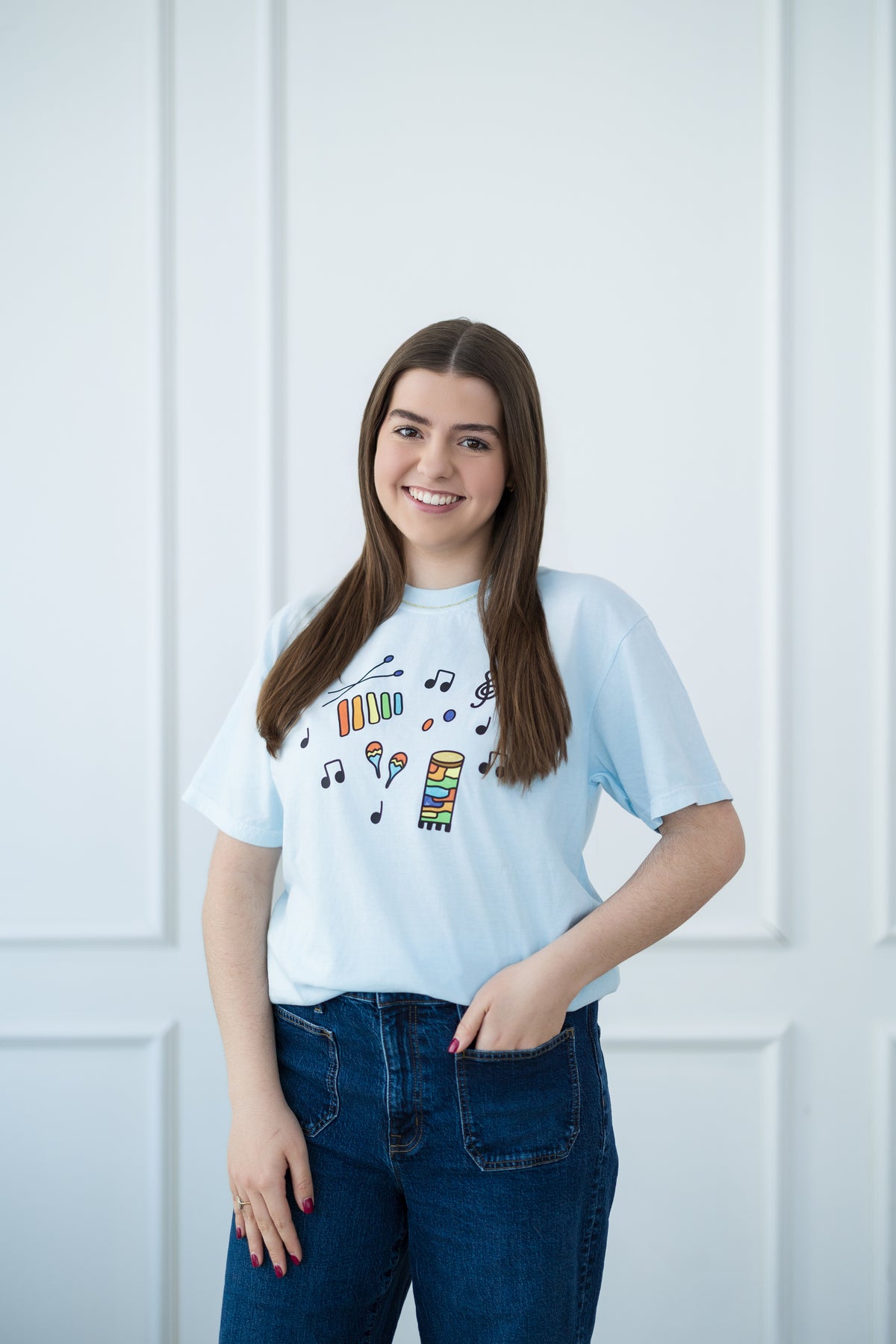 Person wearing a light blue t-shirt with colorful instrument graphics against a white background