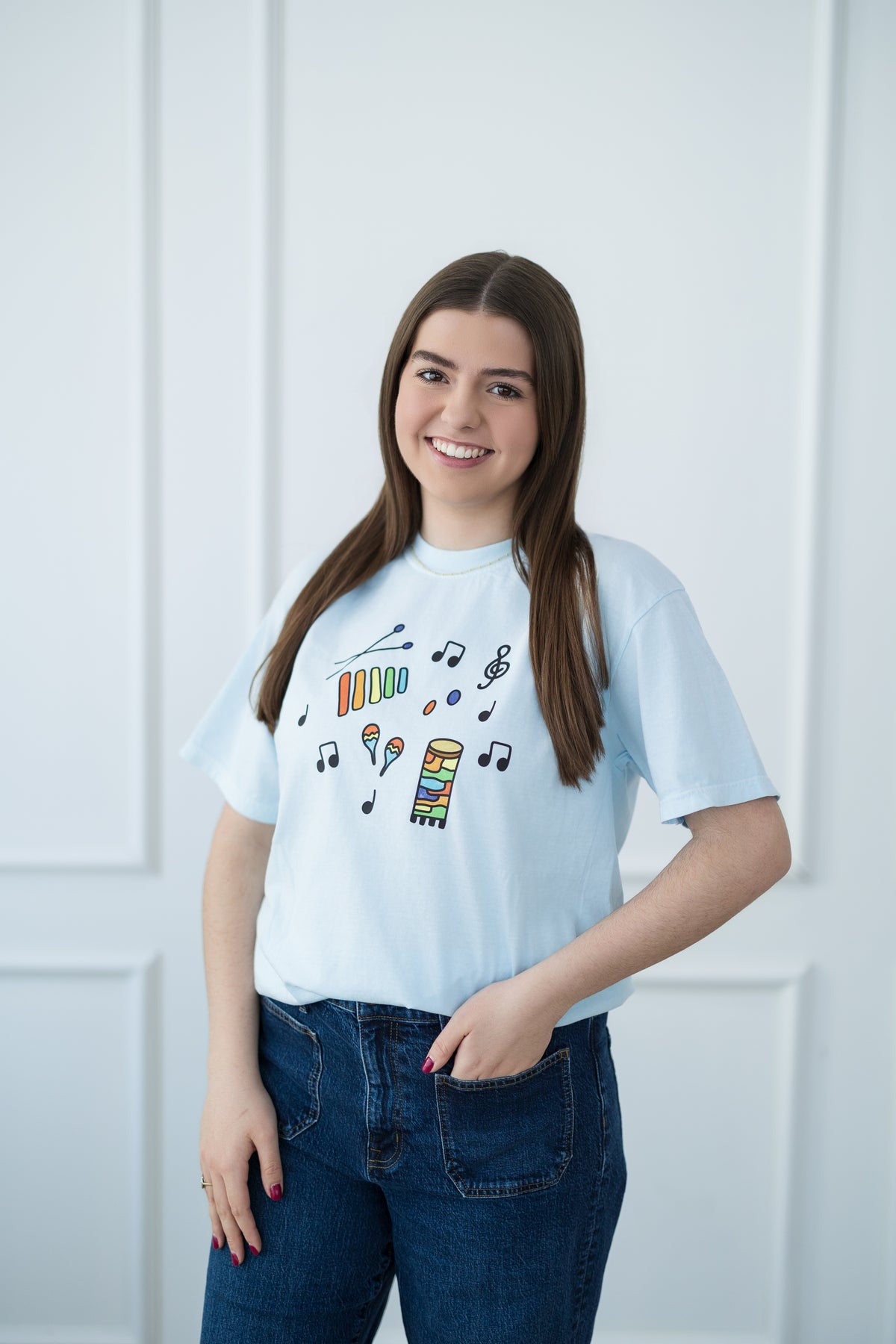 Woman wearing a light blue t-shirt with colorful graphic design against a white background