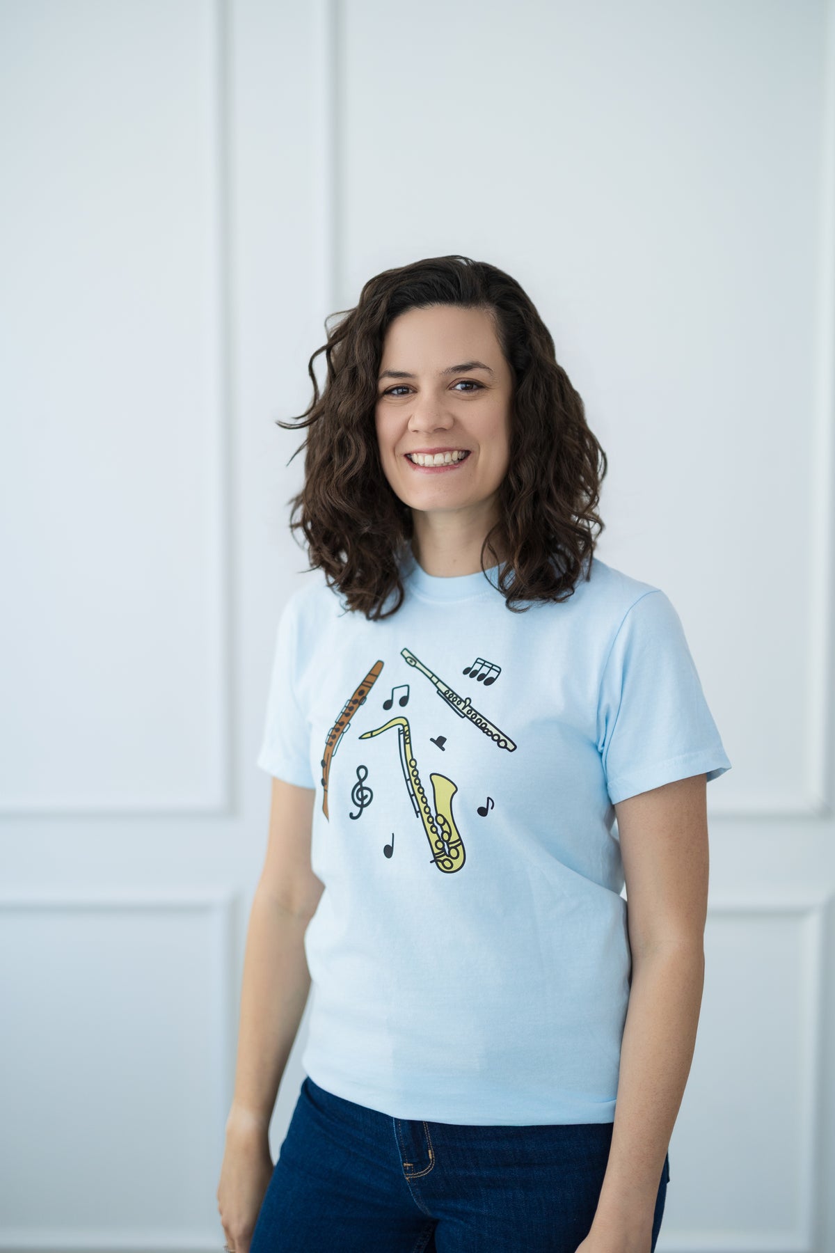 Woman wearing a light blue t-shirt with a saxophone design against a white background