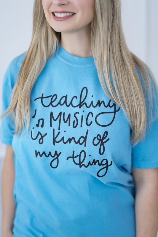 Person wearing a blue t-shirt with 'Teaching Music is kind of my thing' text.