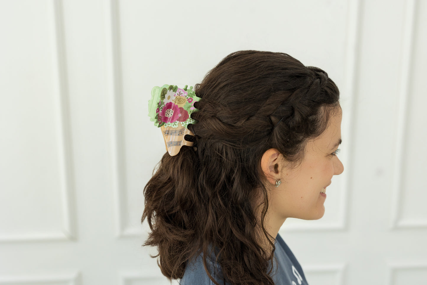 Woman with braided hair wearing a floral hair clip against a white background