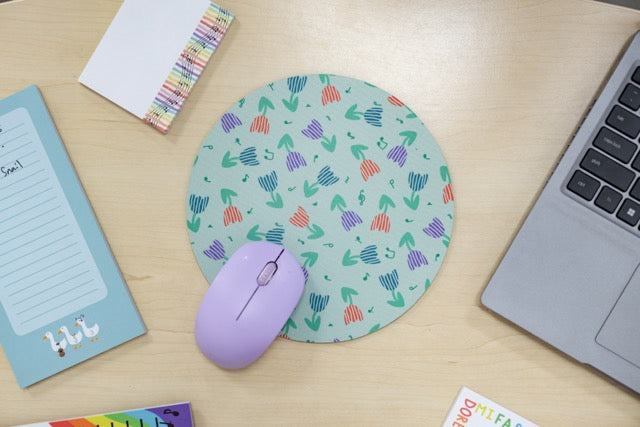 Round mouse pad with colorful pattern on a desk with a laptop and mouse.
