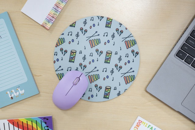 Mouse pad with musical pattern on a desk with a laptop and mouse.