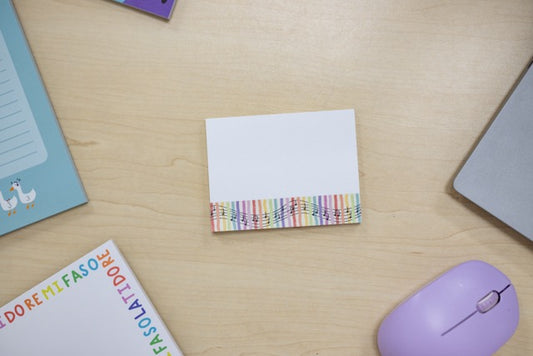 Colorful striped sticky notes on a wooden desk with a mouse and books.
