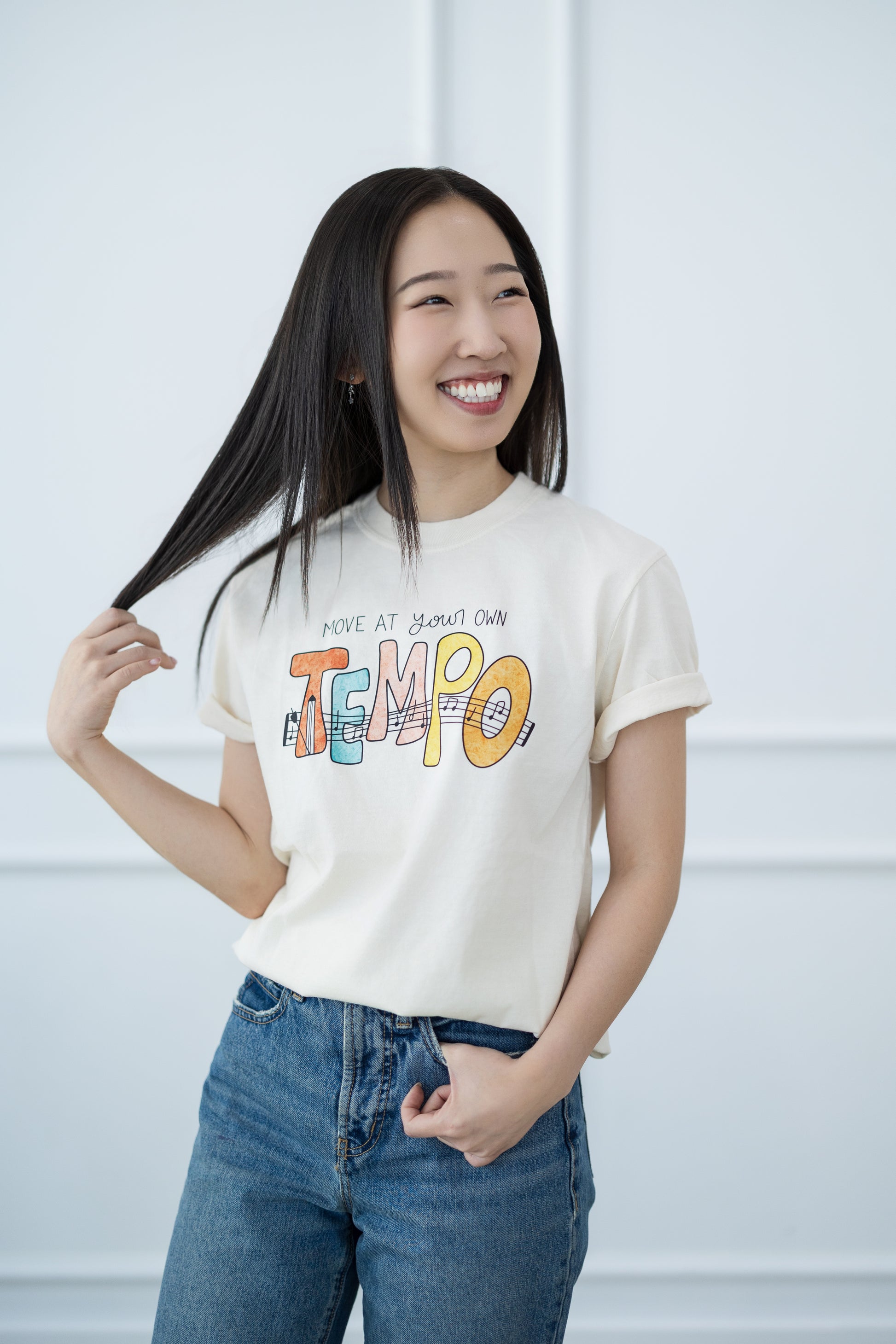 Woman wearing a white t-shirt with colorful text design against a light background
