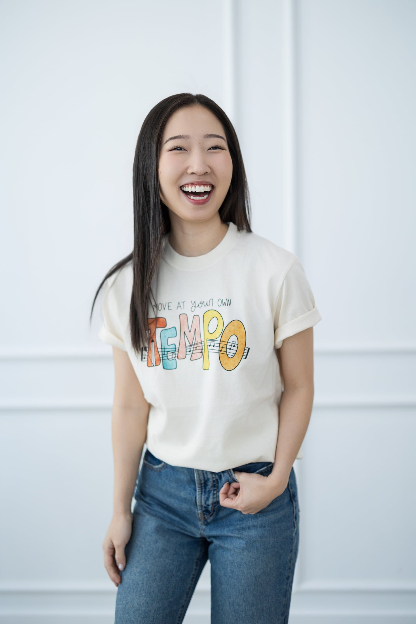 Woman wearing a white t-shirt with colorful text against a light background