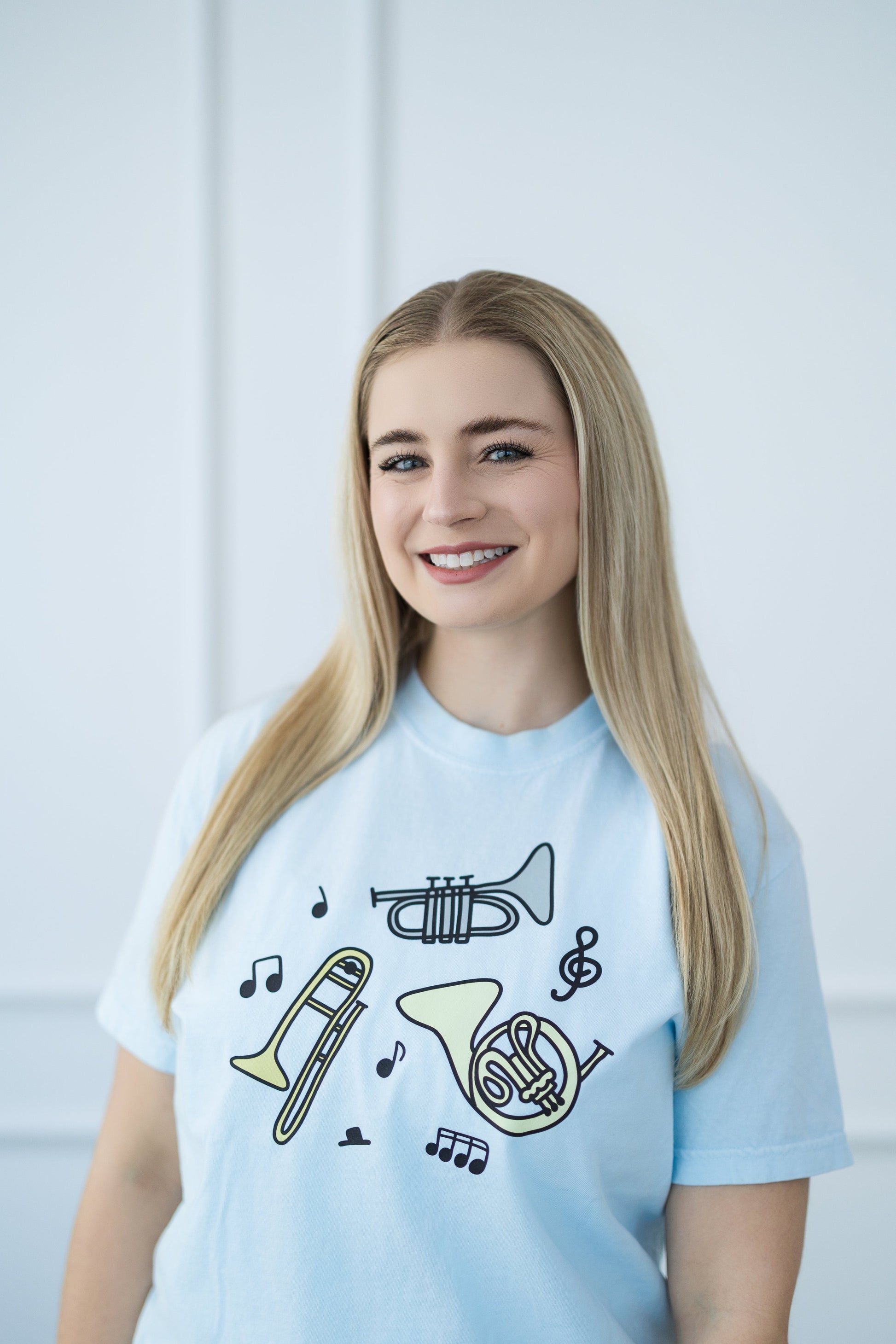 Person wearing a light blue t-shirt with musical instrument designs on a white background