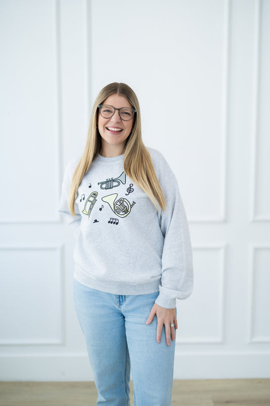 Woman wearing a light gray sweatshirt with musical instrument designs against a white background