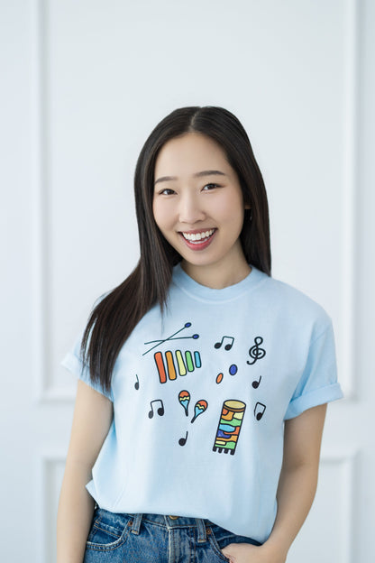 Woman wearing a light blue t-shirt with colorful designs against a white background