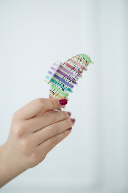 Hand holding a colorful hair clip against a light background