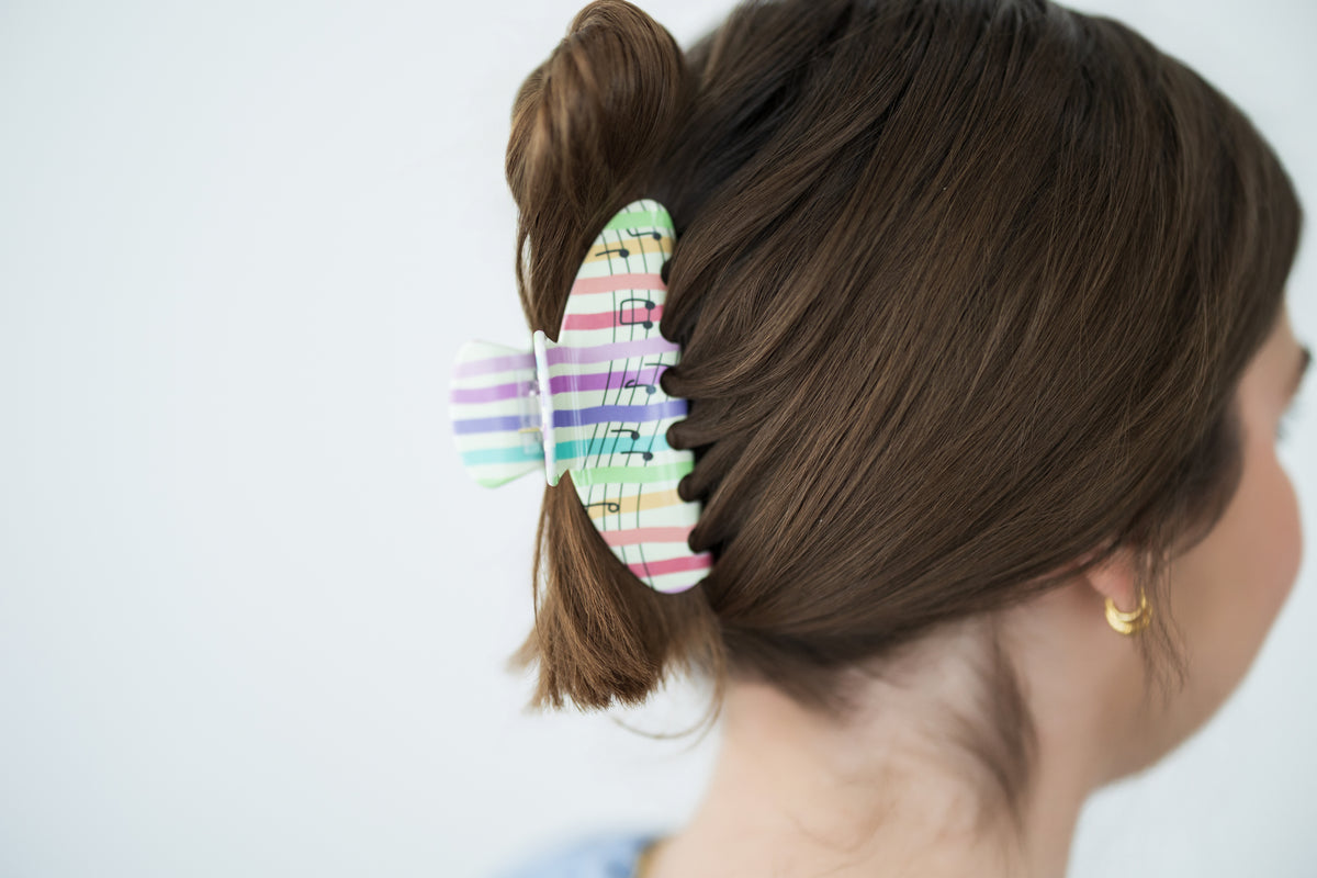 Person with a colorful hair clip in their hair against a plain background