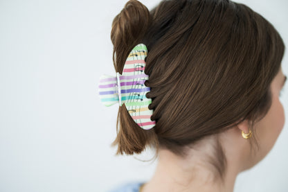 Person with a colorful hair clip in their hair against a plain background