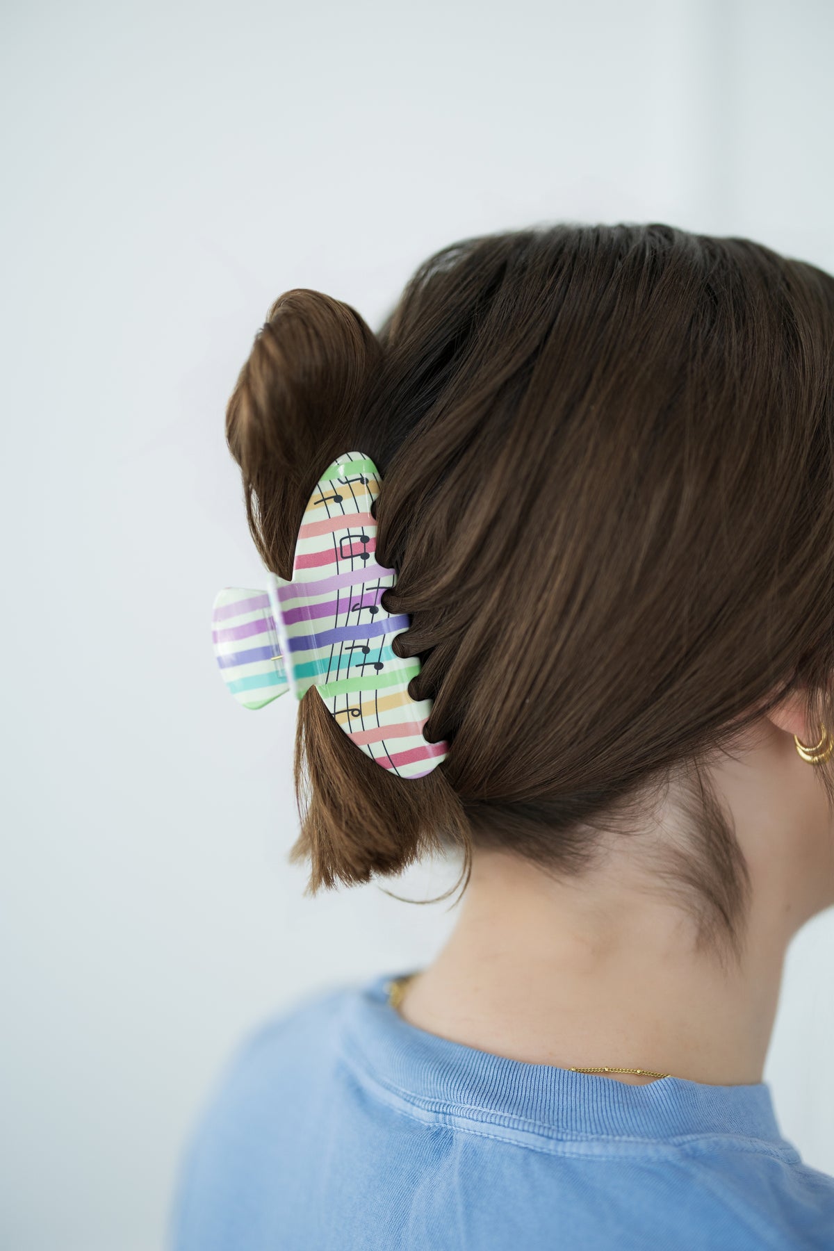 Person with a colorful hair clip in their hair against a plain background
