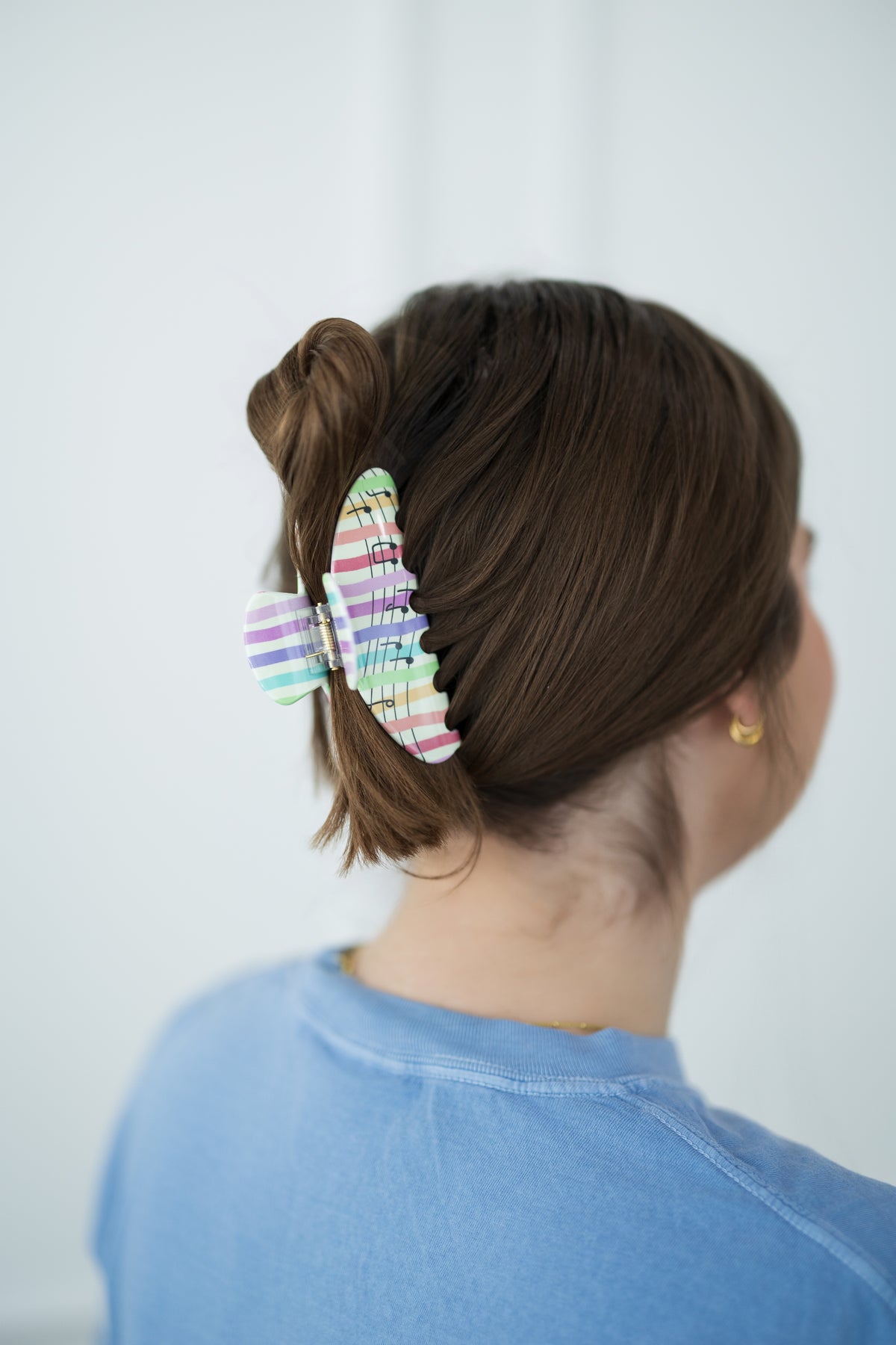 Person with a colorful hair clip in their bun against a plain background
