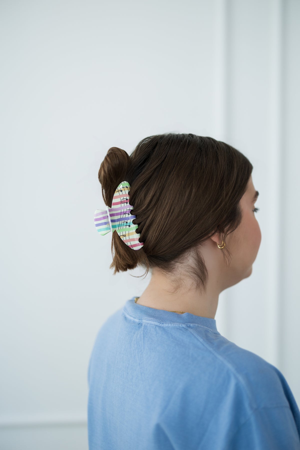 Person with a colorful hair clip in their bun against a white background