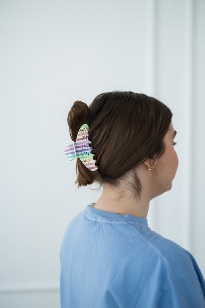 Person with a colorful hair clip in their bun against a white background