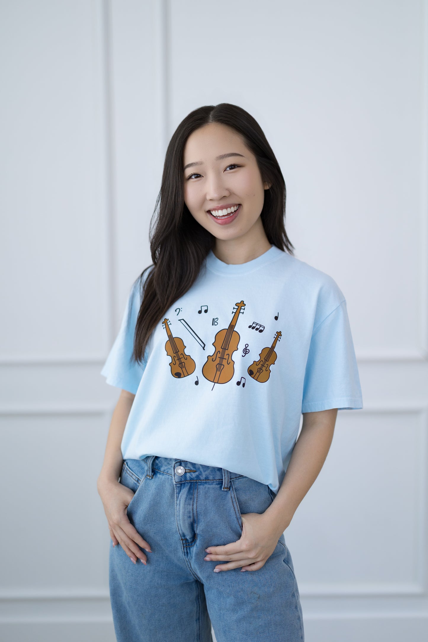 Woman wearing a light blue t-shirt with musical instrument designs against a white background