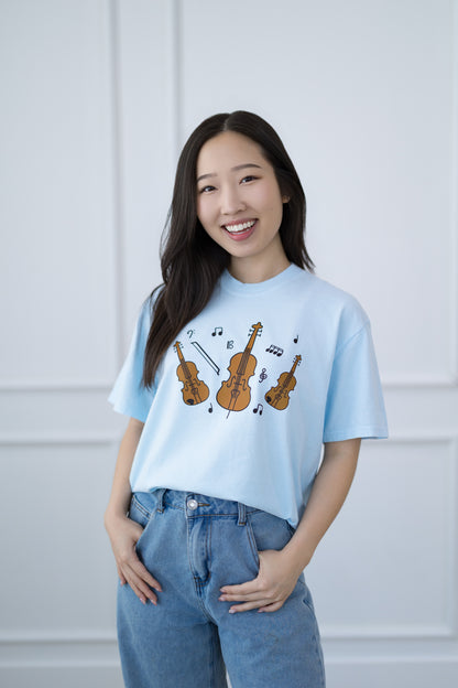Woman wearing a light blue t-shirt with musical instrument designs against a white background