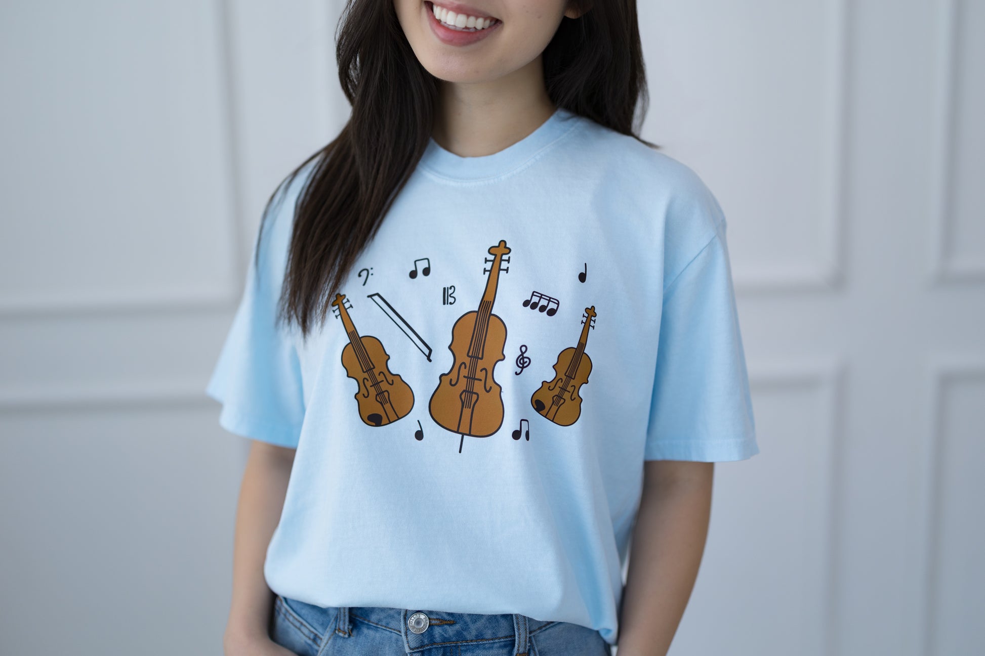 Person wearing a light blue t-shirt with musical instrument designs.