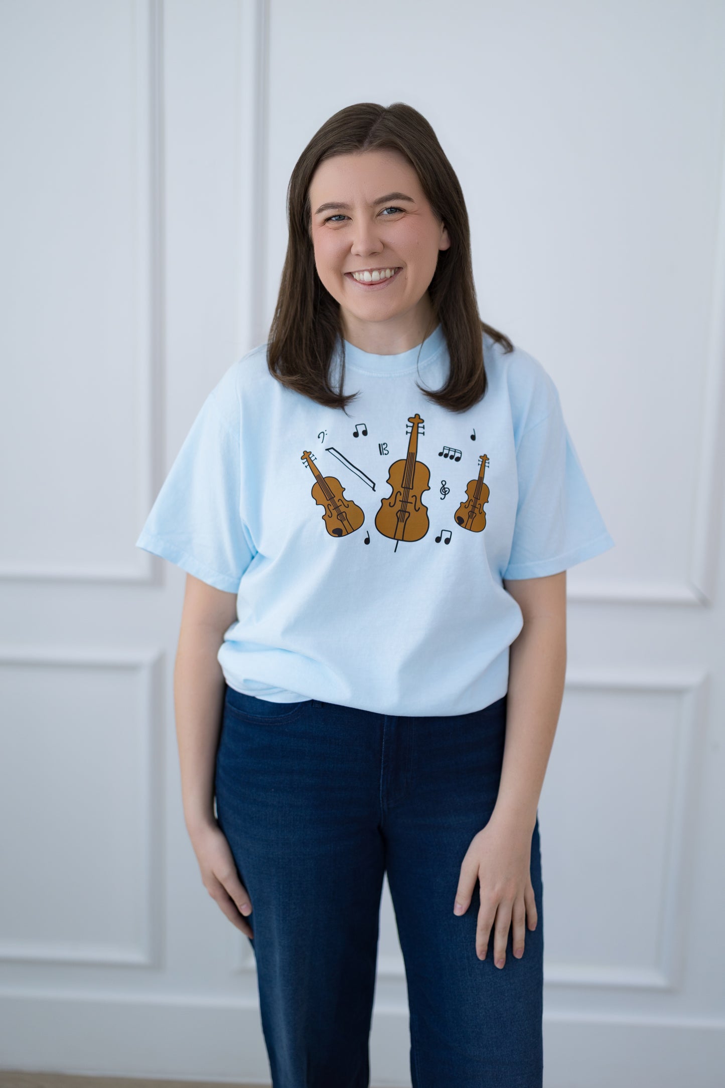 Person wearing a light blue t-shirt with musical instrument design against a white background