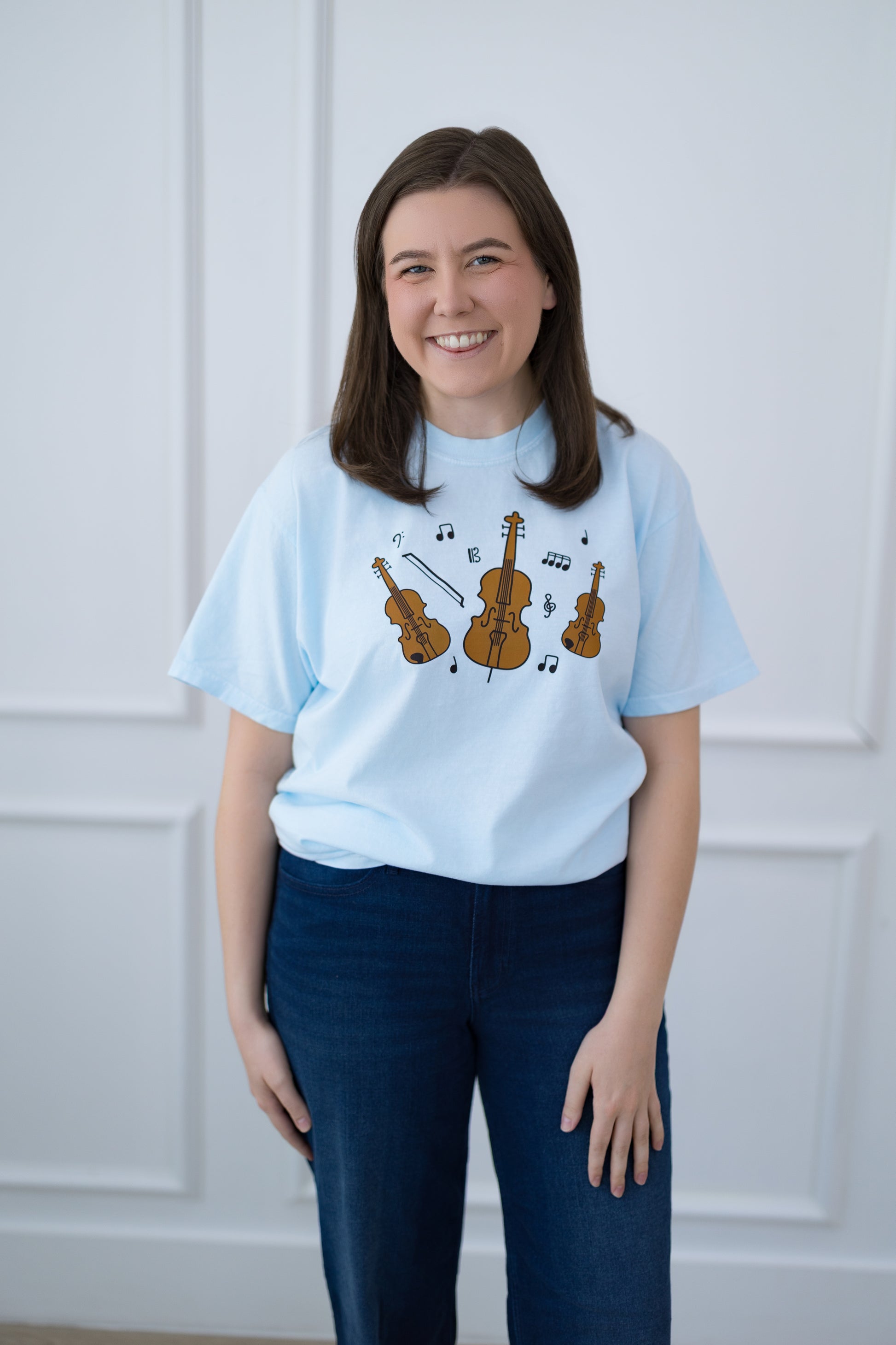 Person wearing a light blue t-shirt with musical instrument design against a white background