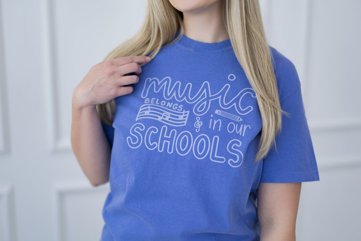 Person wearing a blue t-shirt with 'Music Belongs in Our Schools' text.