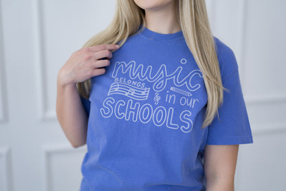 Person wearing a blue t-shirt with 'Music Belongs in Our Schools' text.