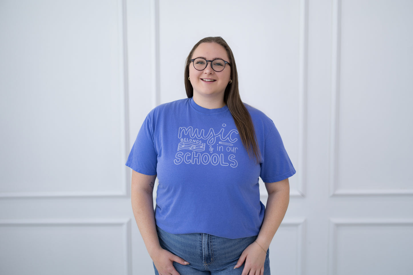 Person wearing a blue t-shirt with text against a white paneled wall