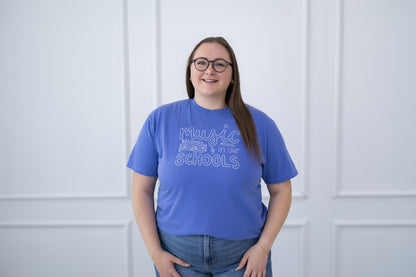 Person wearing a blue t-shirt with text against a white paneled wall