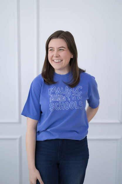 Person wearing a blue t-shirt with text, standing against a light-colored wall.