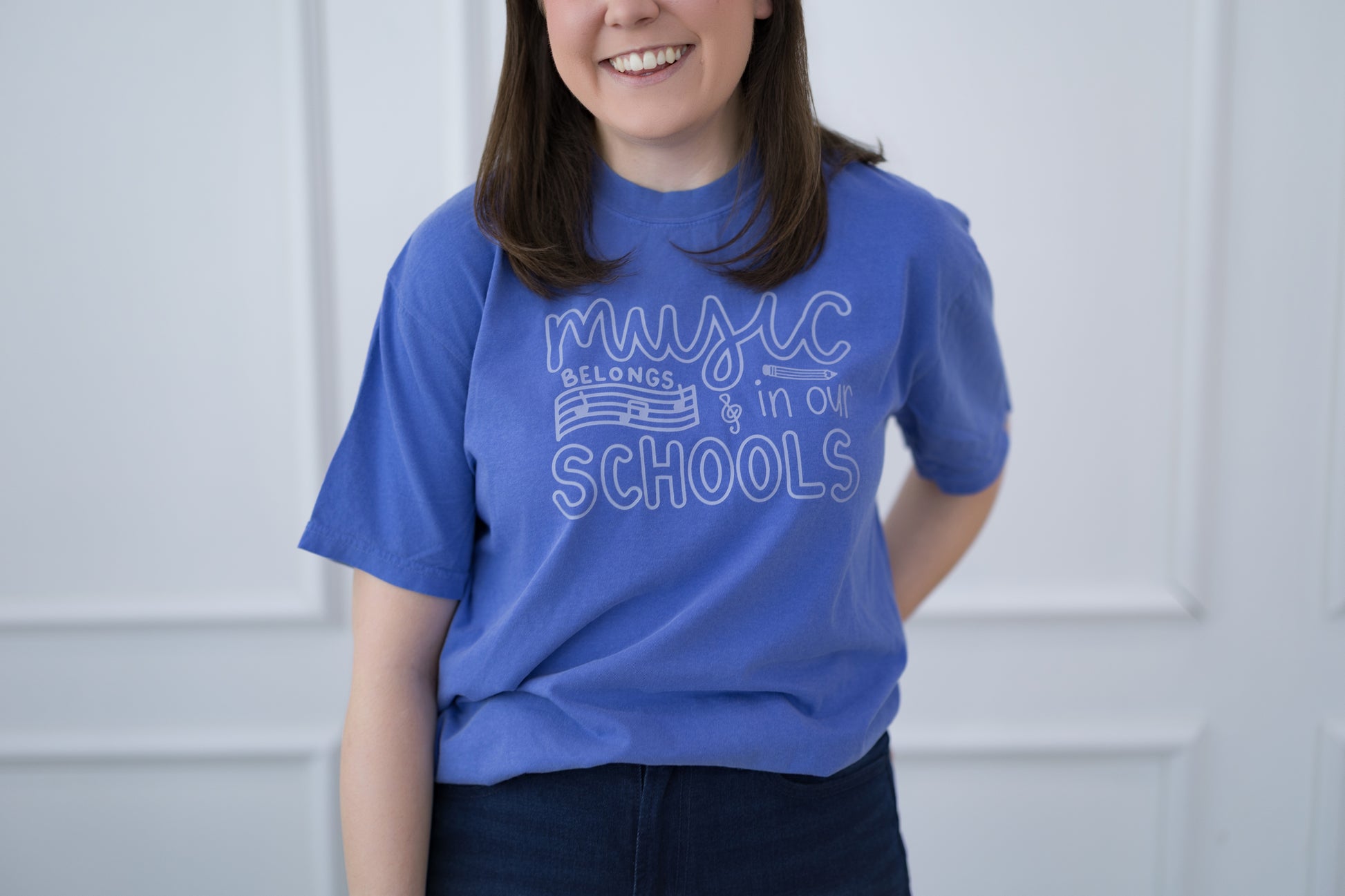 Person wearing a blue t-shirt with text, standing against a plain background