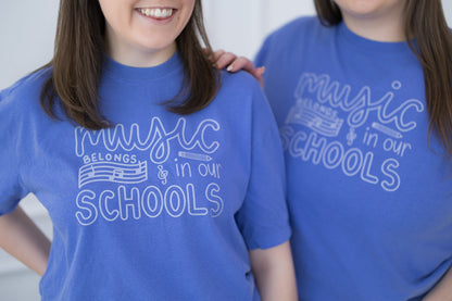 Two people wearing blue t-shirts with 'Music Belongs in Our Schools' text.