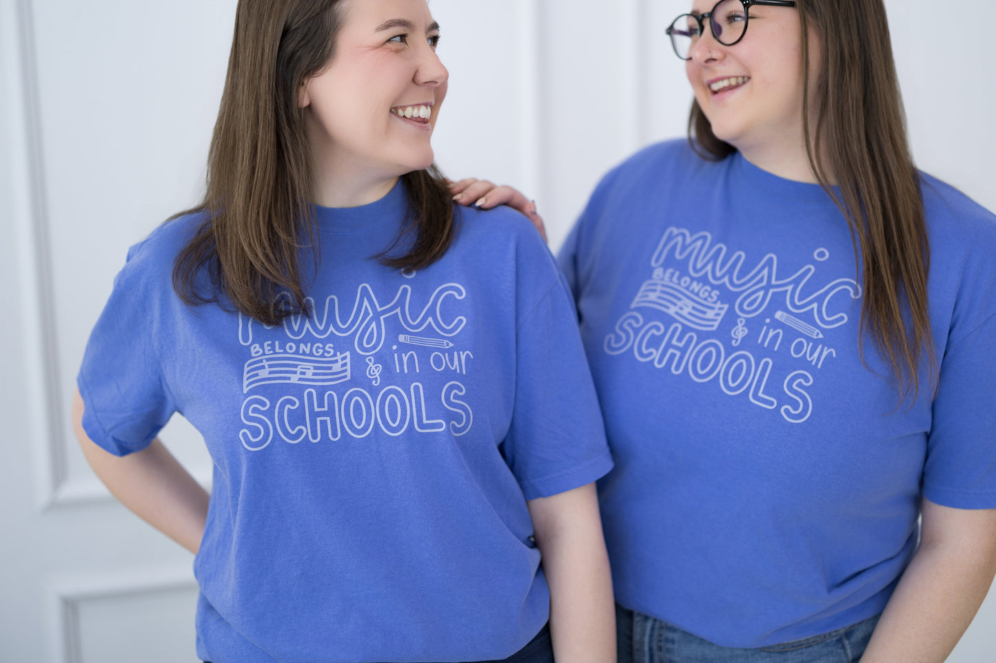 Two people wearing blue t-shirts with 'Music belongs in our schools' text.