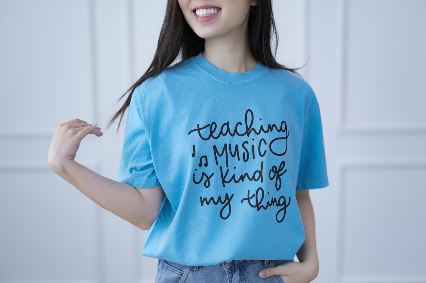 Person wearing a blue t-shirt with text, standing against a plain background