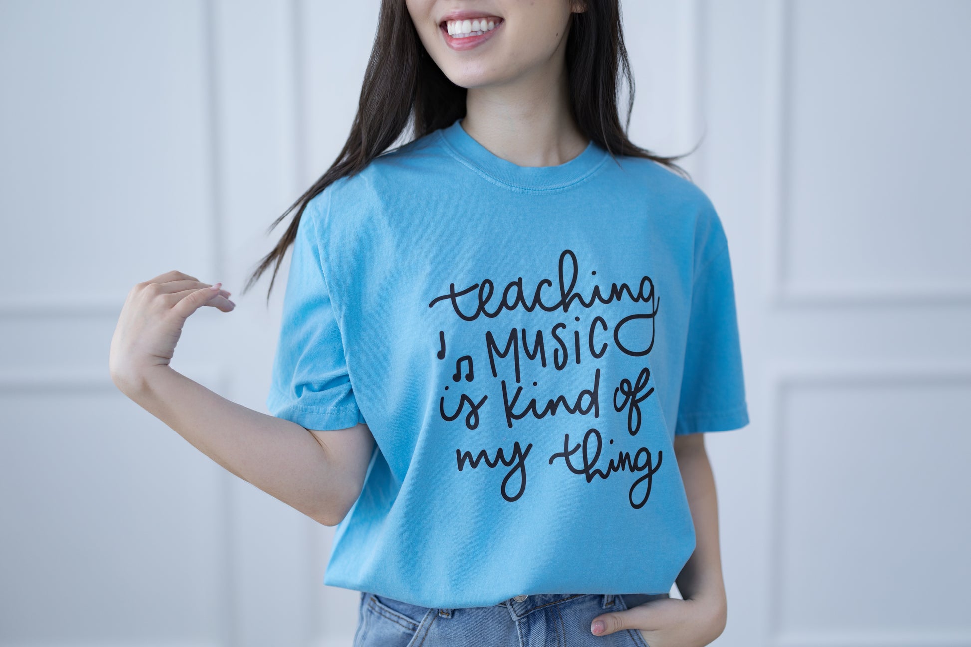 Person wearing a blue t-shirt with text, standing against a plain background