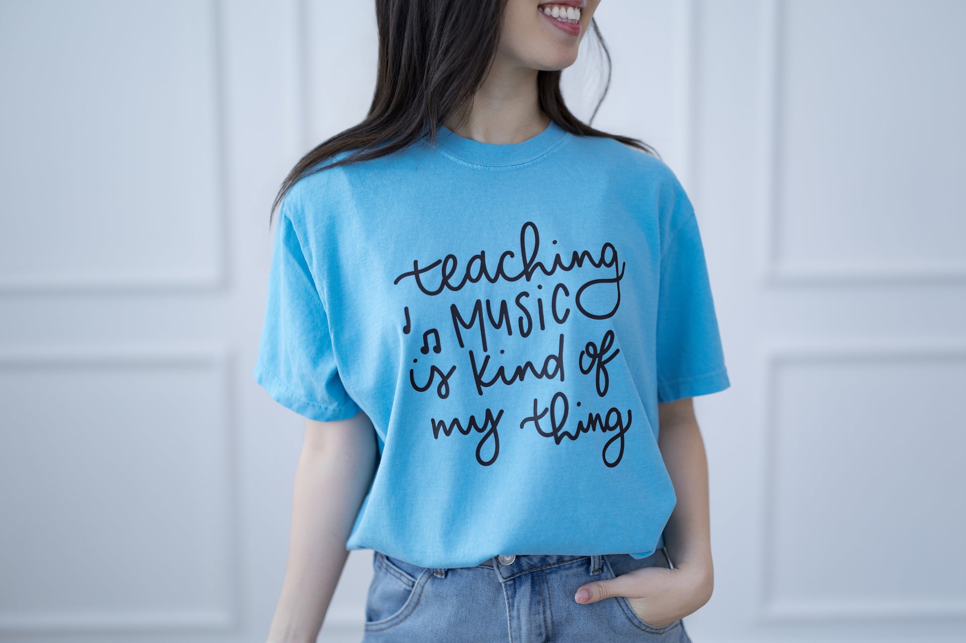 Person wearing a blue t-shirt with 'teaching music is kind of my thing' text.