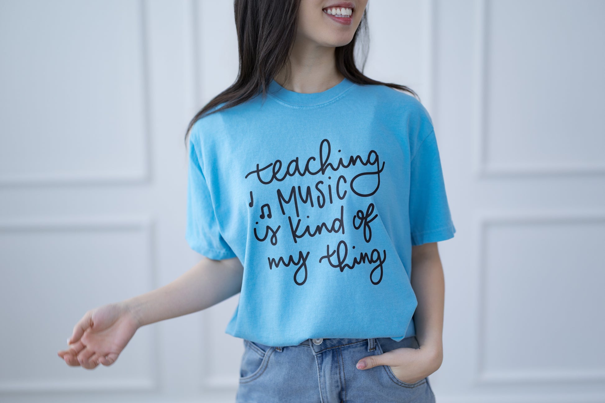 Person wearing a blue t-shirt with 'Teaching music is kind of my thing' text.
