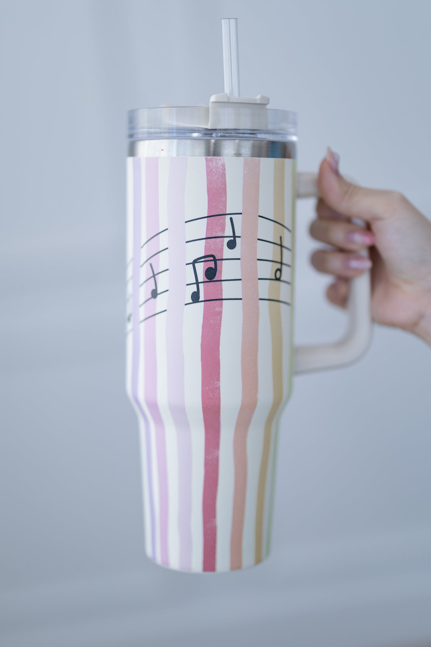 Striped mug with musical notes held by a hand against a gray background