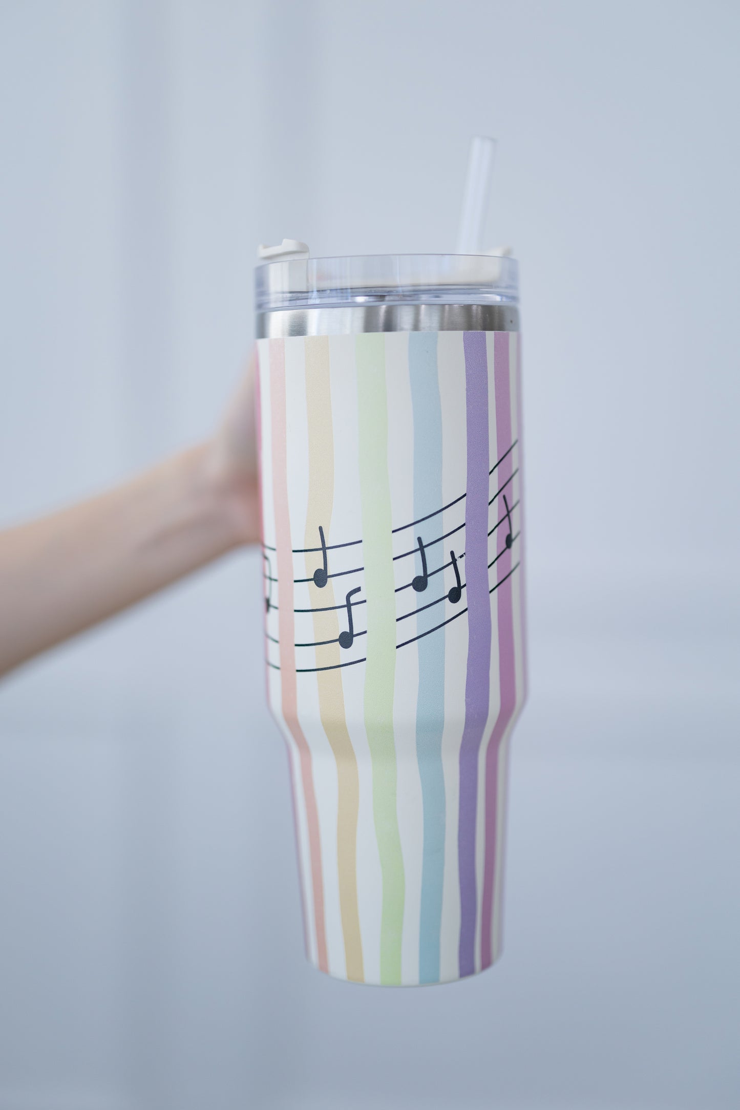 Tumbler with striped design and musical notes held against a plain background