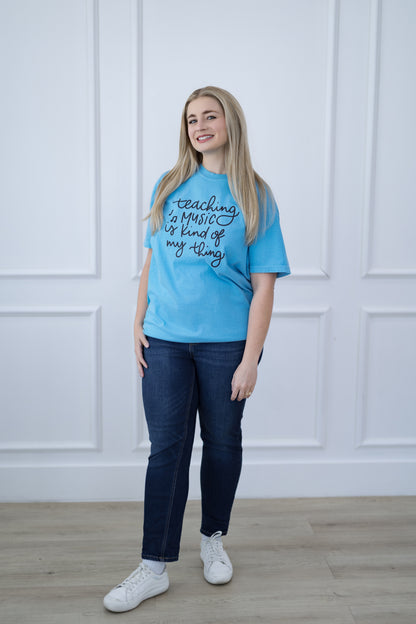 Person wearing a blue t-shirt with text, standing against a white paneled wall.
