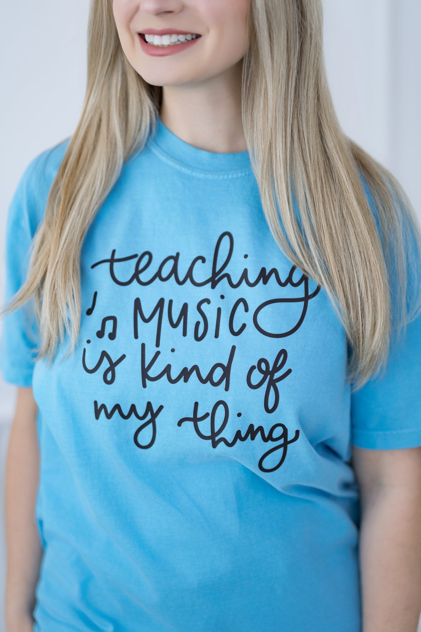 Person wearing a blue t-shirt with 'Teaching Music is kind of my thing' text.